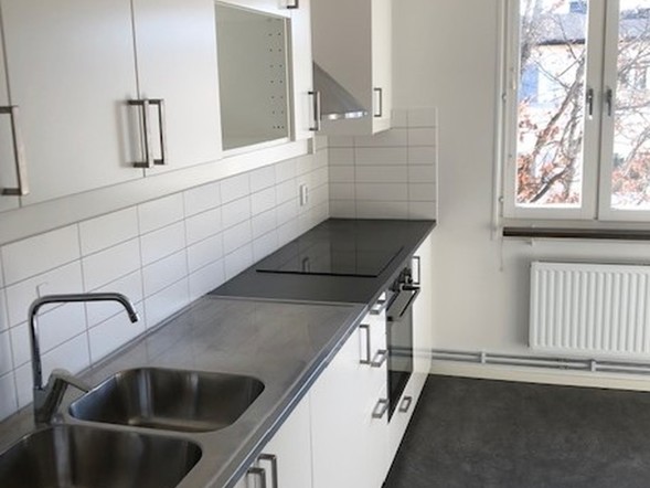 Vitt kök med mörk arbetsbänk och fönster i en hyreslägenhet i Västerås.