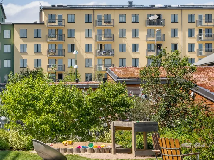 Innergård med lekplats, cykelparkering och flerbostadshus i bakgrunden.