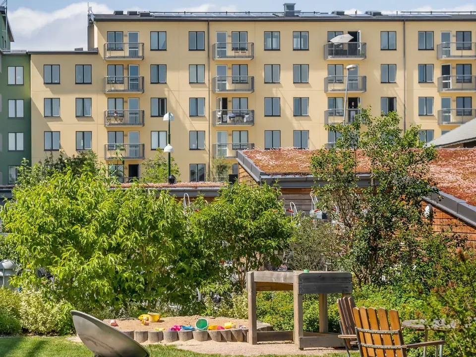 Innergård med lekplats, cykelparkering och flerbostadshus i bakgrunden.