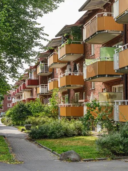 fastigheter-stockholm-hagsatra-tegelbyggnad-balkonger-gangvag.webp