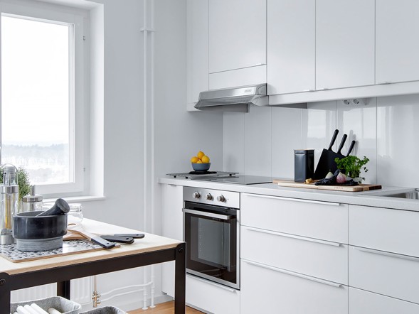 Modernt vitt kök med inbyggd ugn och fönster i en hyreslägenhet i Västerås.