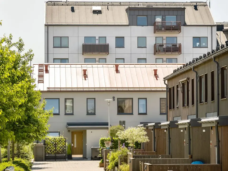 Radhus och flerbostadshus med innergård och grönska mellan husen.