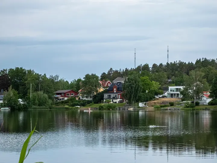Hus vid sjö med reflektioner i vattnet.