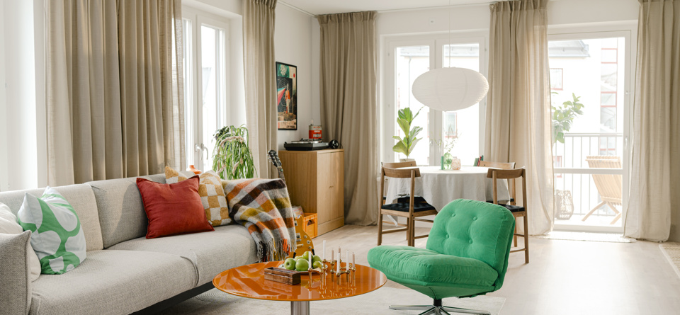 Ljust vardagsrum med soffa, fåtölj, soffbord och matplats.