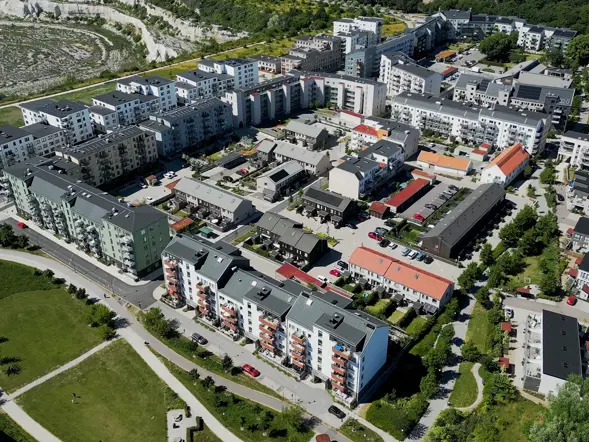 Flygbild över bostadsområde med flerbostadshus, radhus och grönområden.