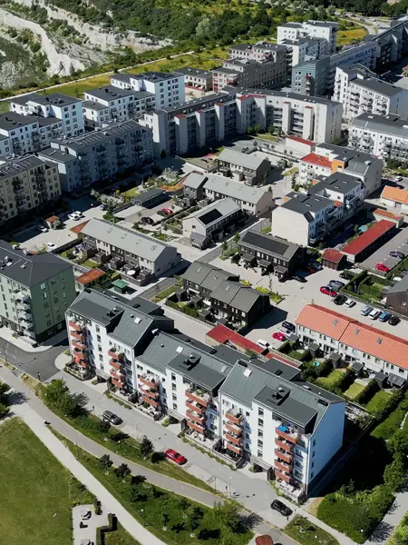 Flygbild över bostadsområde med flerbostadshus, radhus och grönområden.