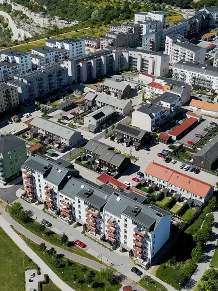 Flygbild över bostadsområde med flerbostadshus, radhus och grönområden.