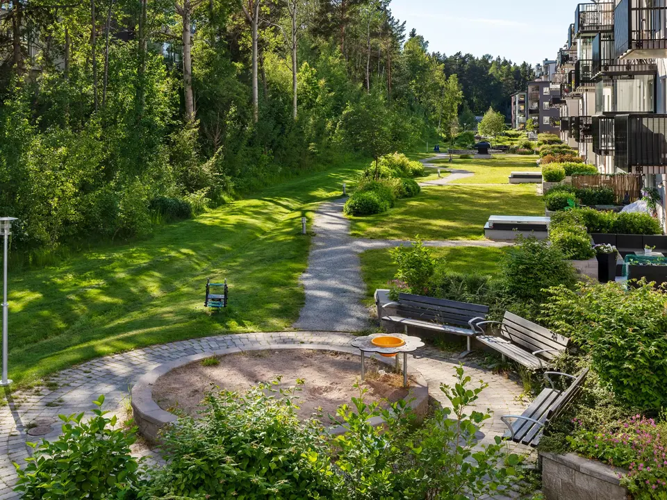 Grön bostadsgård med gångväg och planteringar i Skogsstjärnan i Hässelby.