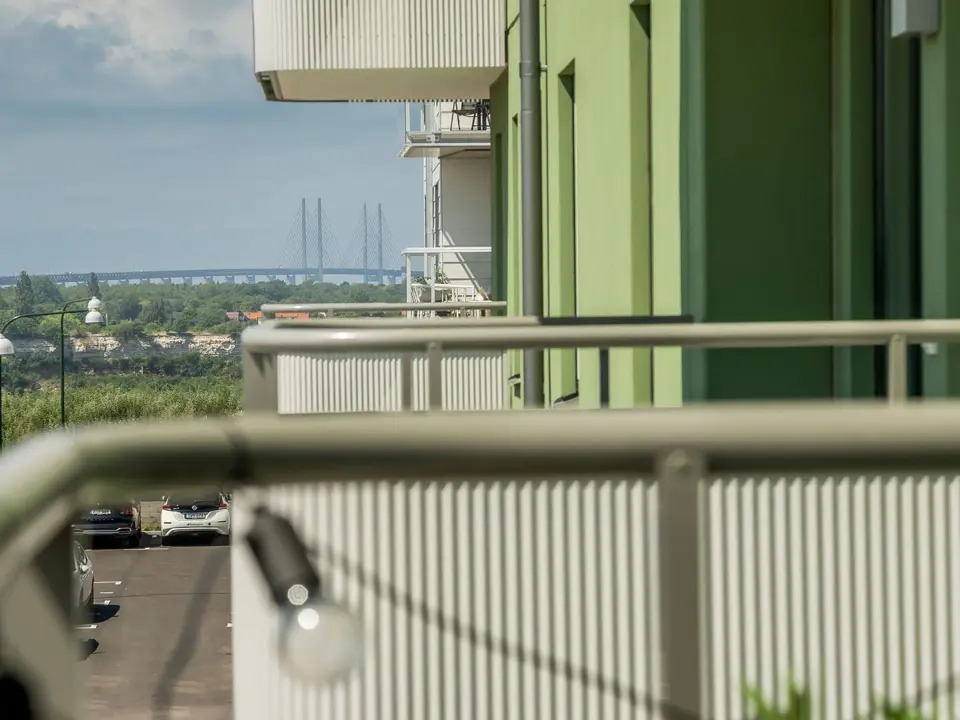 Balkong med utsikt över grönområde och Öresundsbron i bakgrunden.
