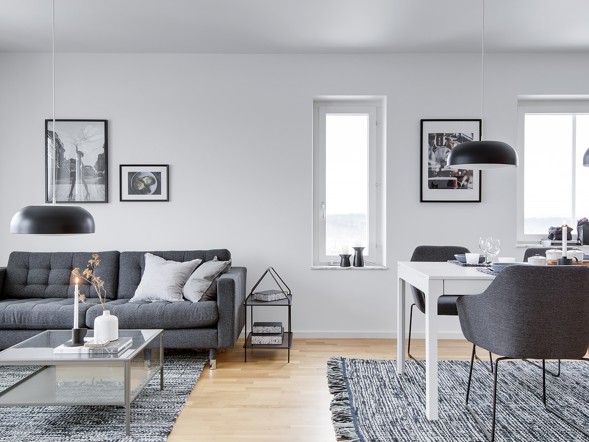 Ljust vardagsrum med matplats och stora fönster i en hyreslägenhet i Västerås.
